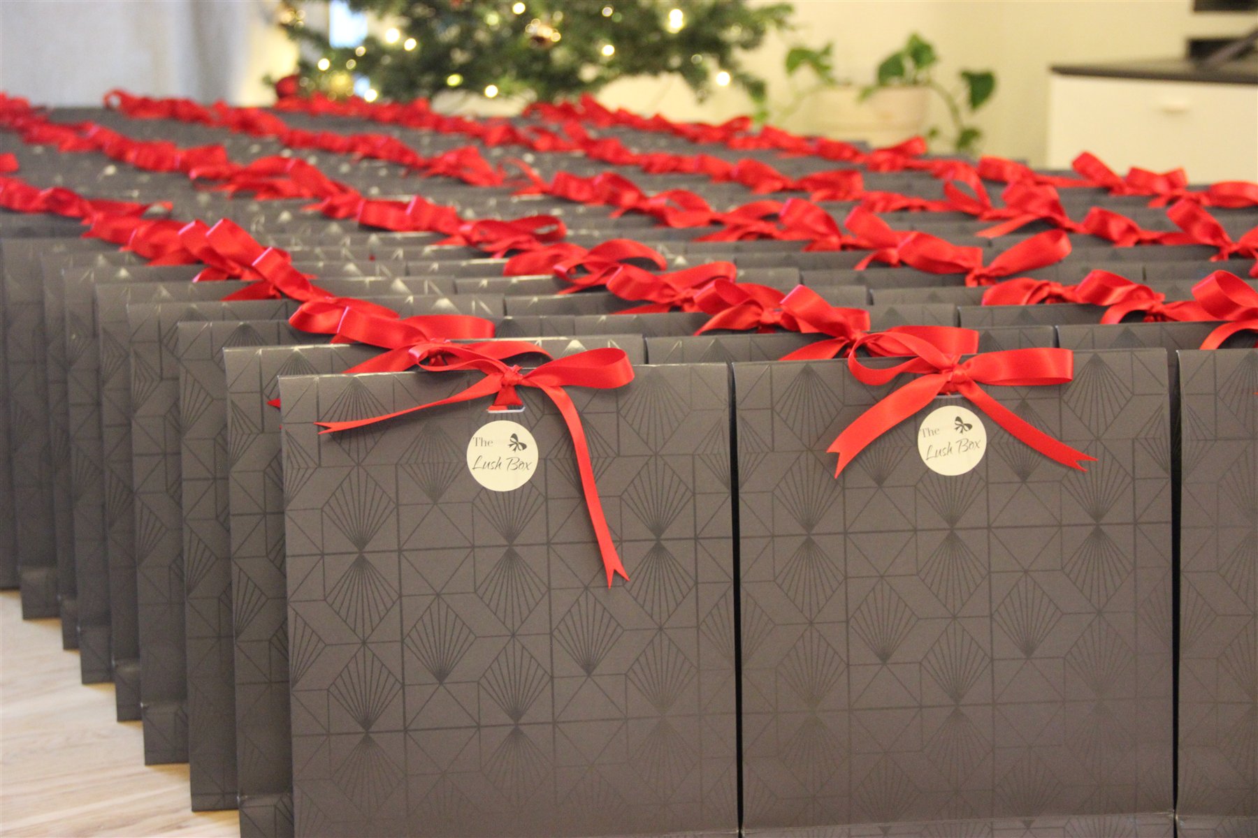 A large group of finished black gift boxes with red ribbons prepared for delivery.